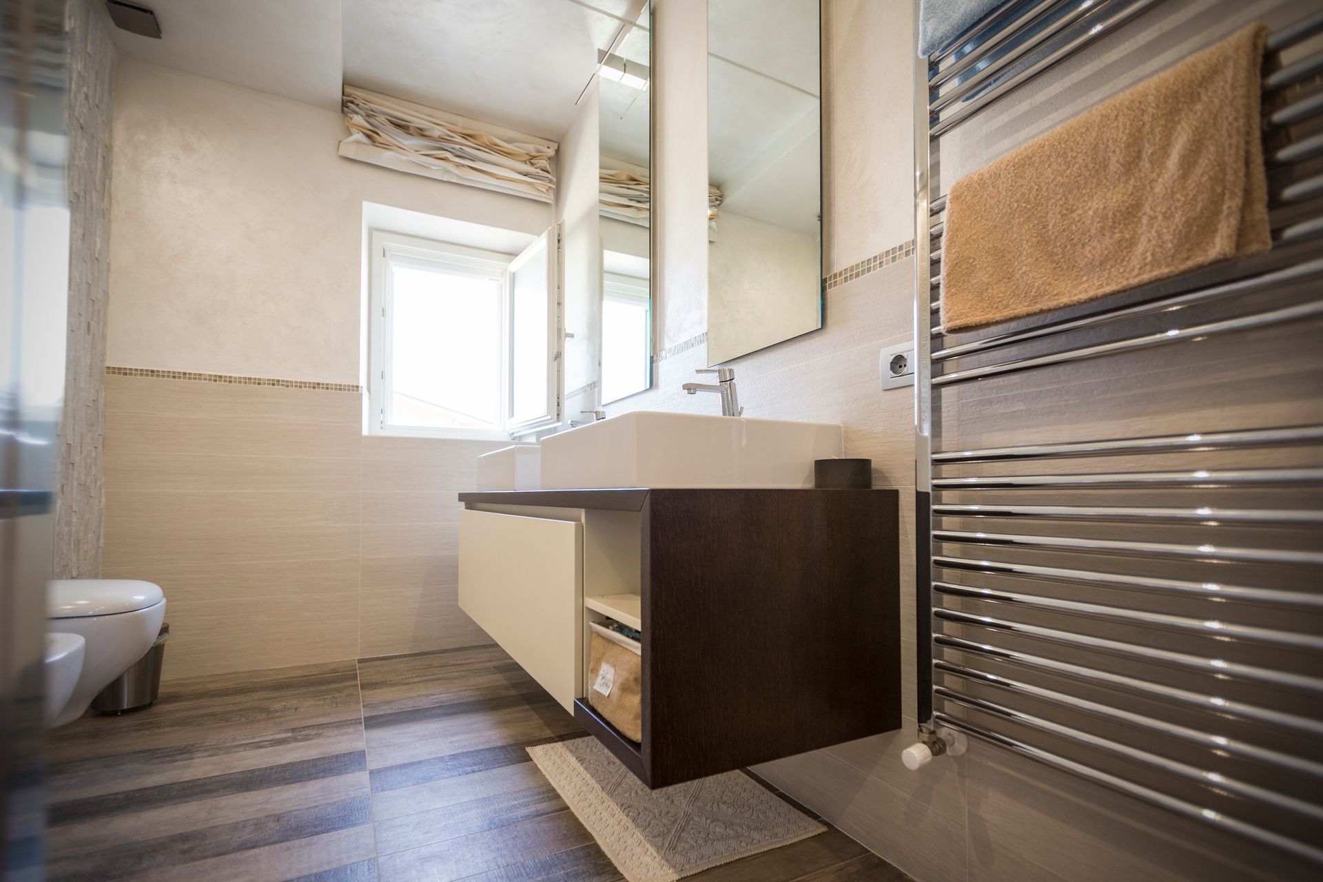 Un bagno con lavandino, water, specchio e portasciugamani.