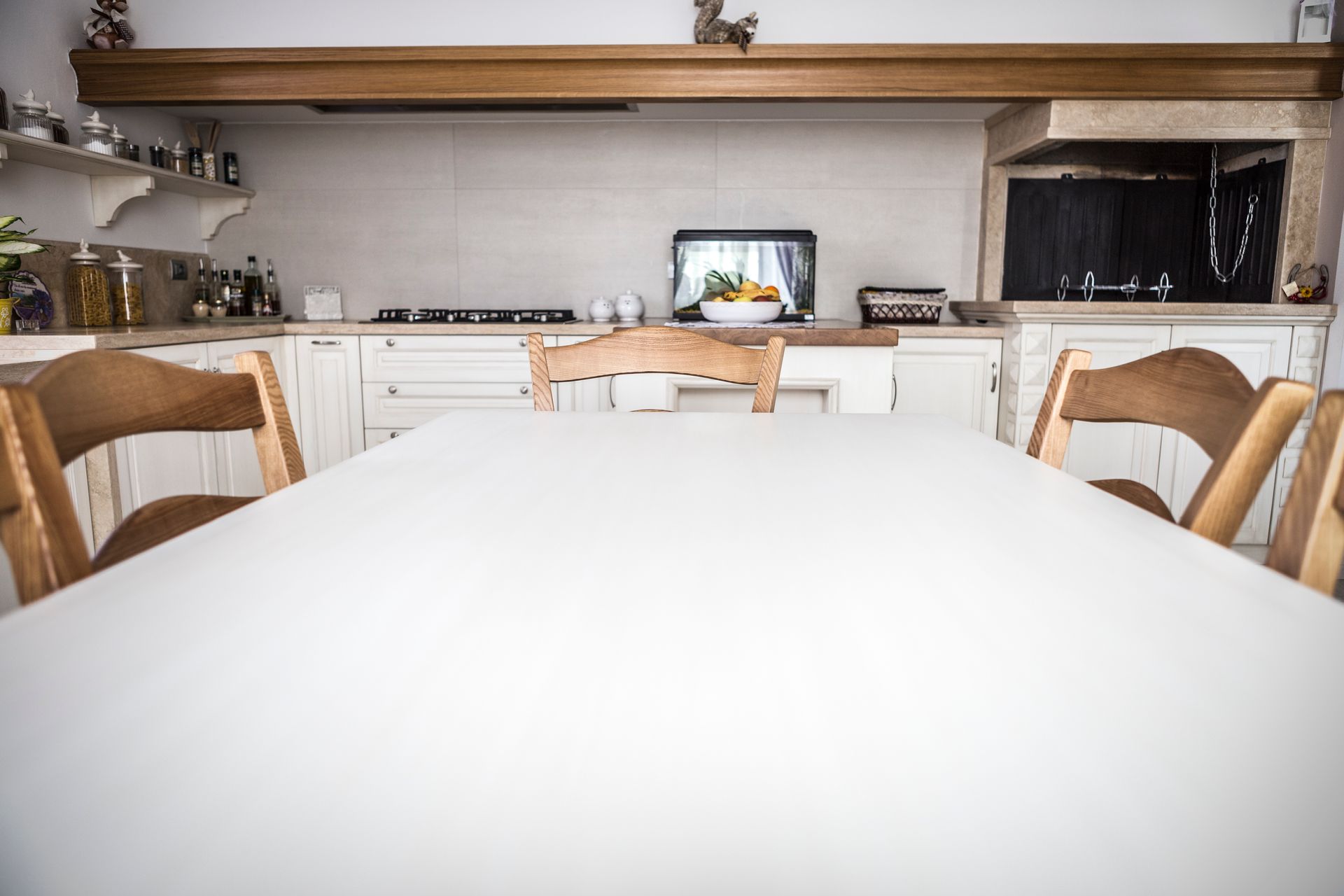 Una cucina con un tavolo bianco e sedie di legno.