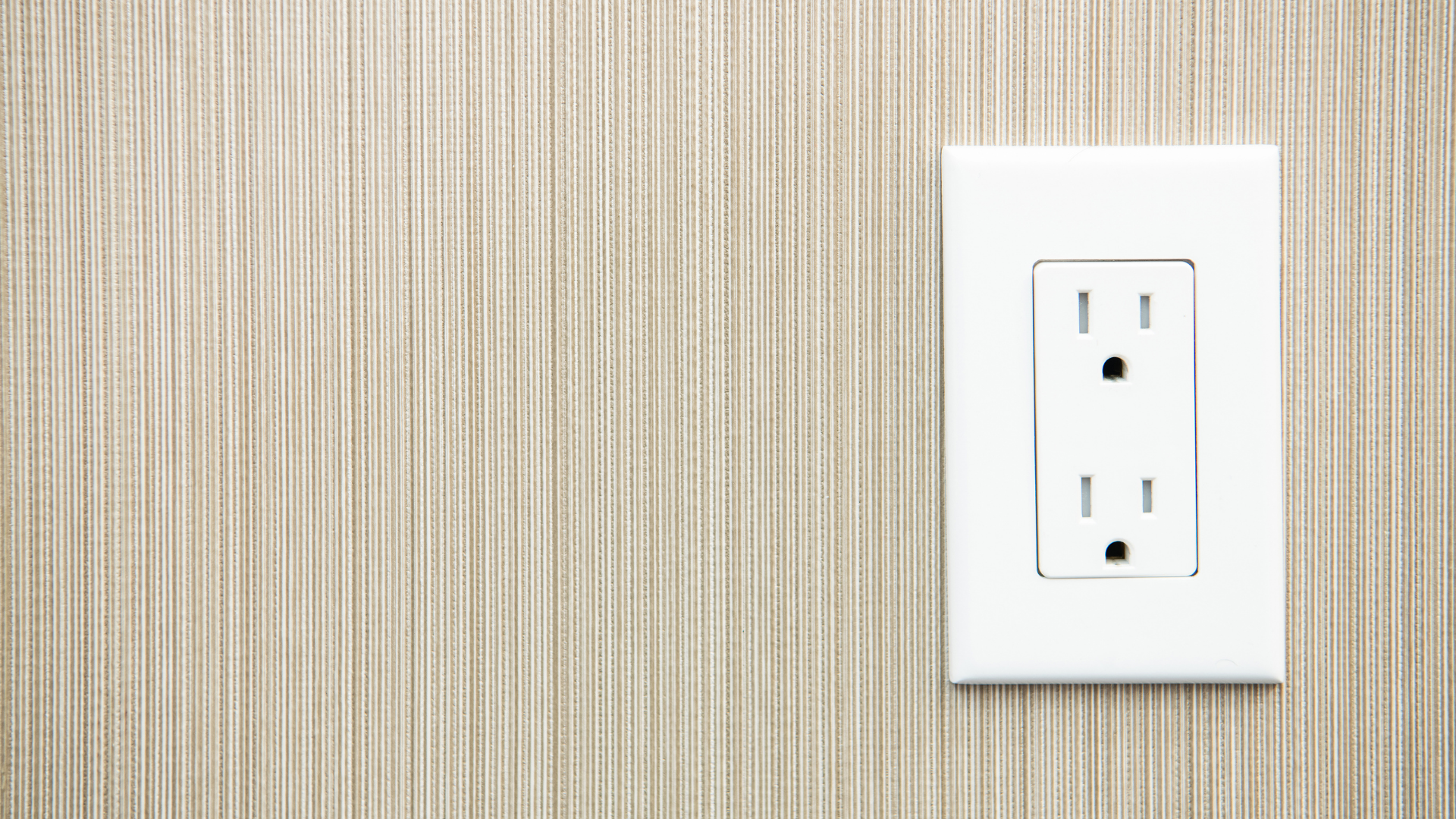 A white electrical outlet on a wooden wall.
