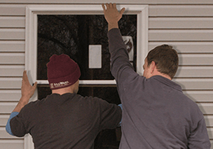 Two men are installing a window on a house
