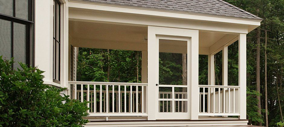 A white house with a porch and a sliding glass door.