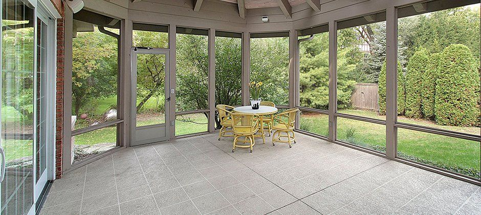 A screened in porch with a table and chairs in it.