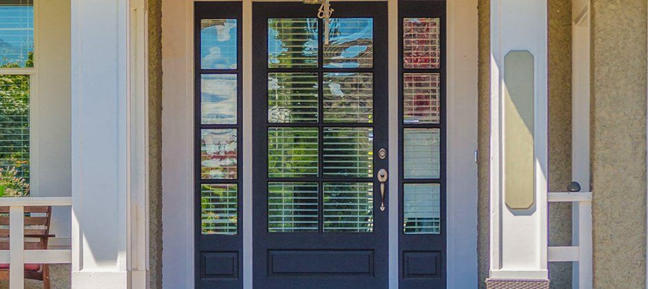 The front door of a house with a porch and a black door.
