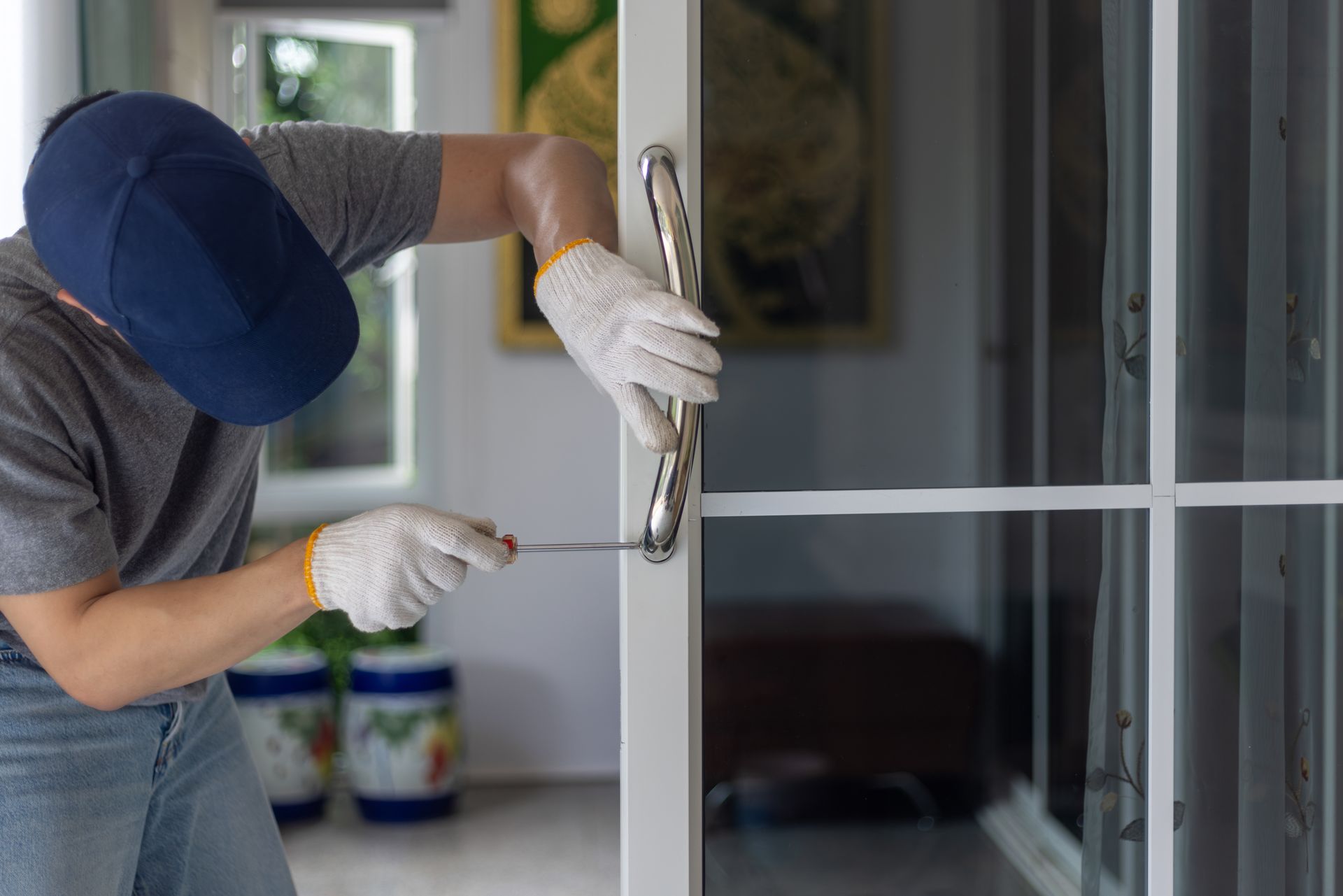 A man is fixing a sliding glass door with a screwdriver.