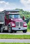 A red dump truck is driving down a road.