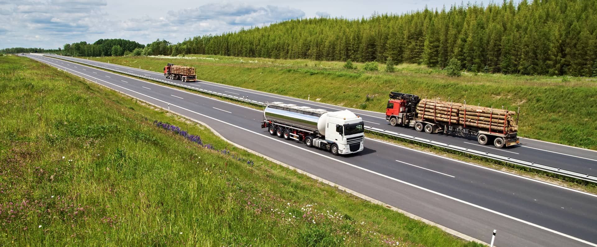 A couple of trucks are driving down a highway.