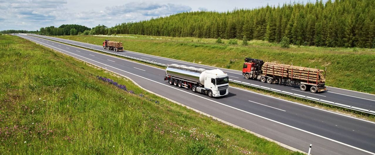 A couple of trucks are driving down a highway.