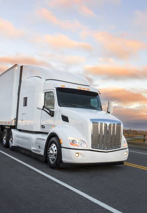 A white semi truck is driving down a highway.