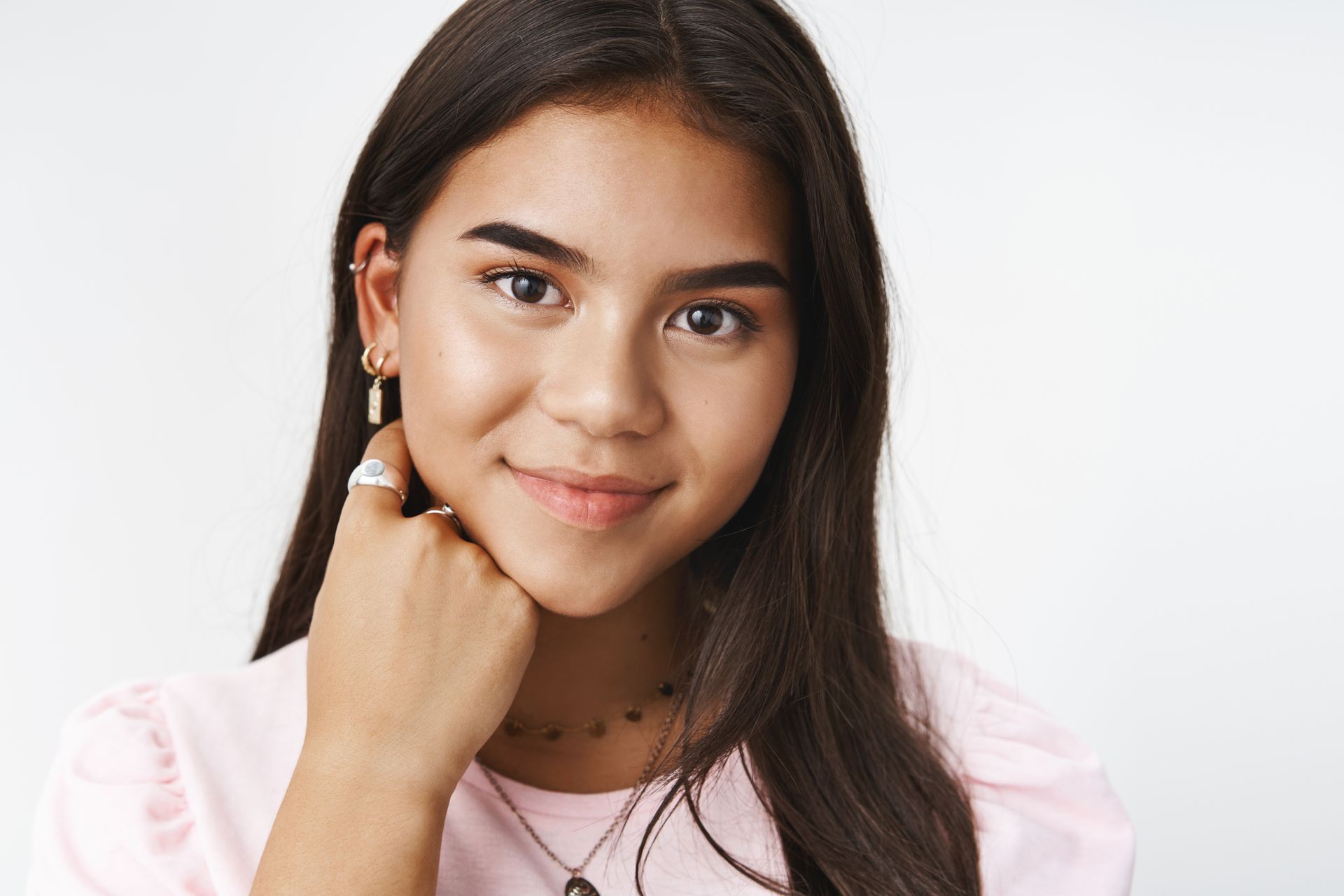A close up of a young woman 's face with her hand on her chin.