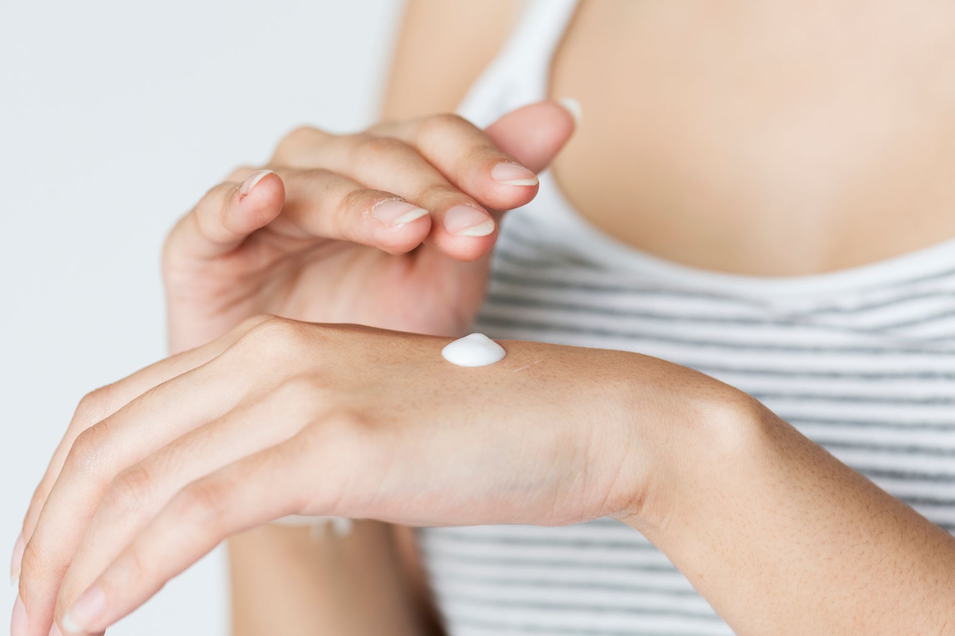 A woman is applying lotion to her wrist.