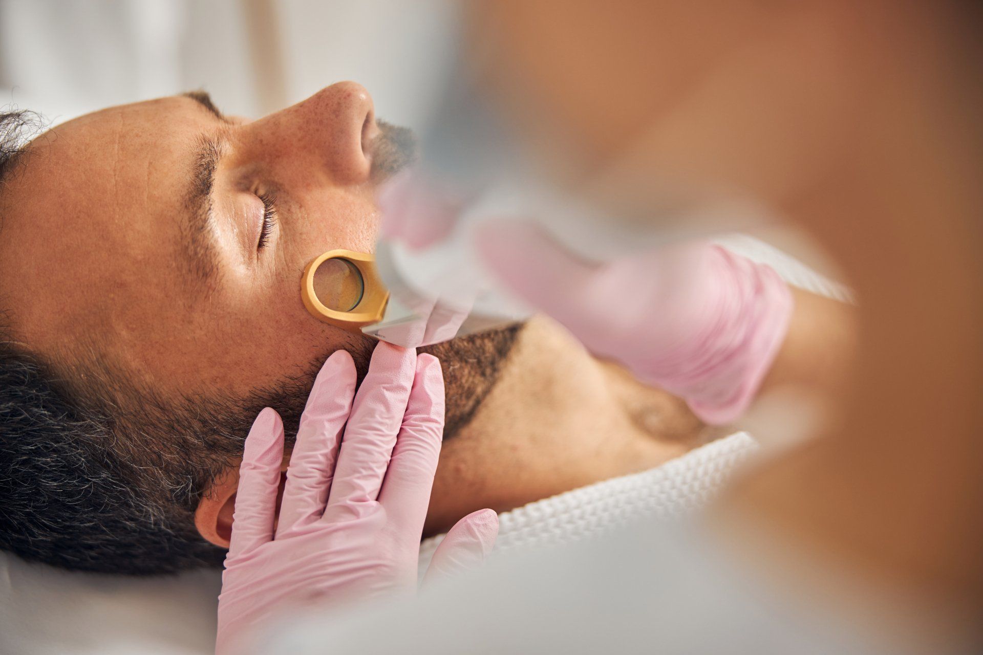 A man is getting a laser treatment on his face.