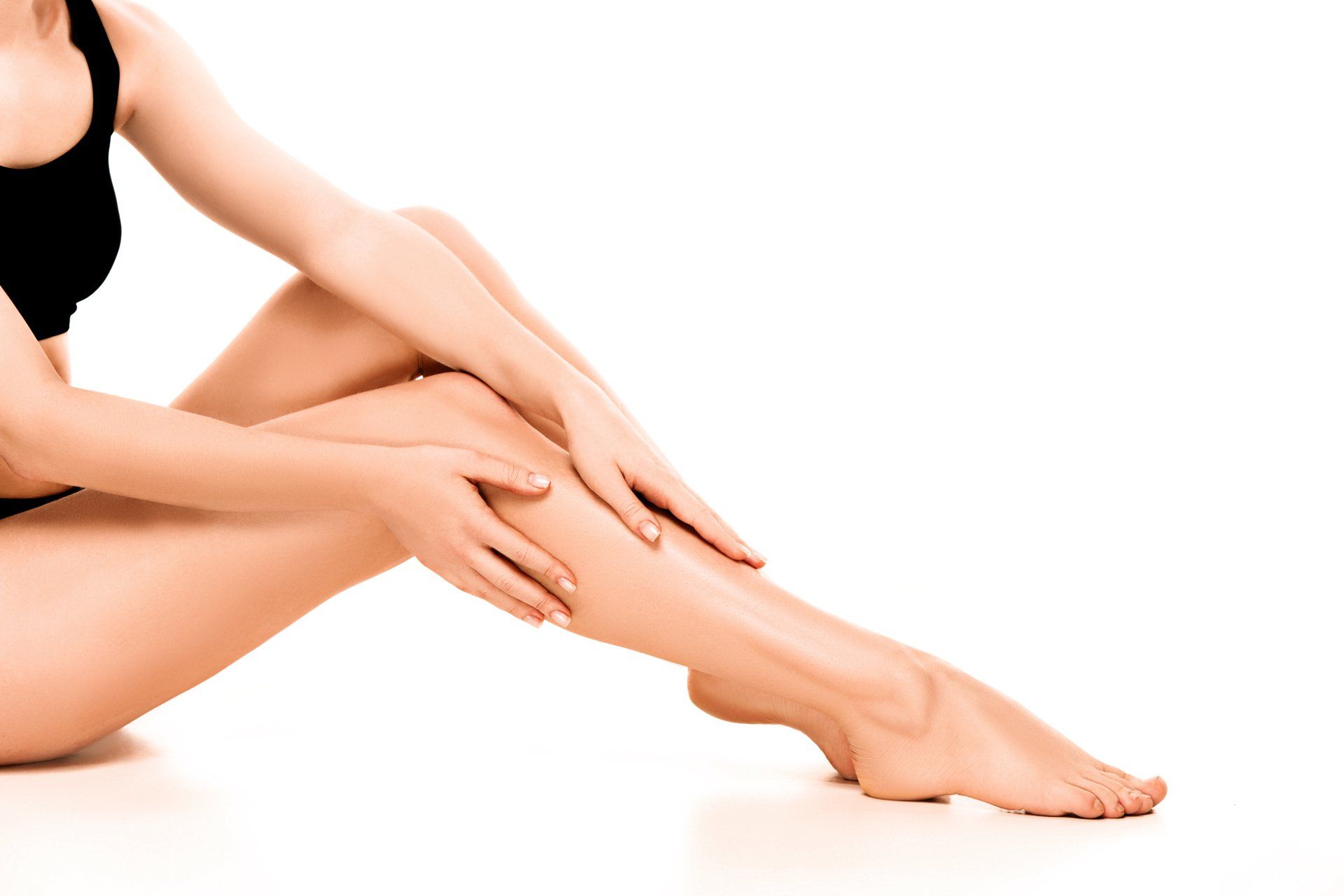 A woman is sitting on the floor with her legs crossed and her hands on her legs.