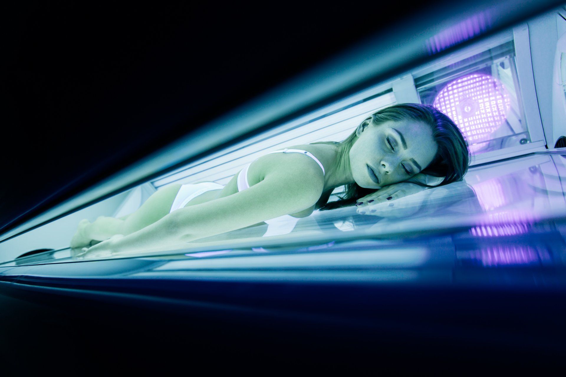 A woman is laying in a tanning bed.