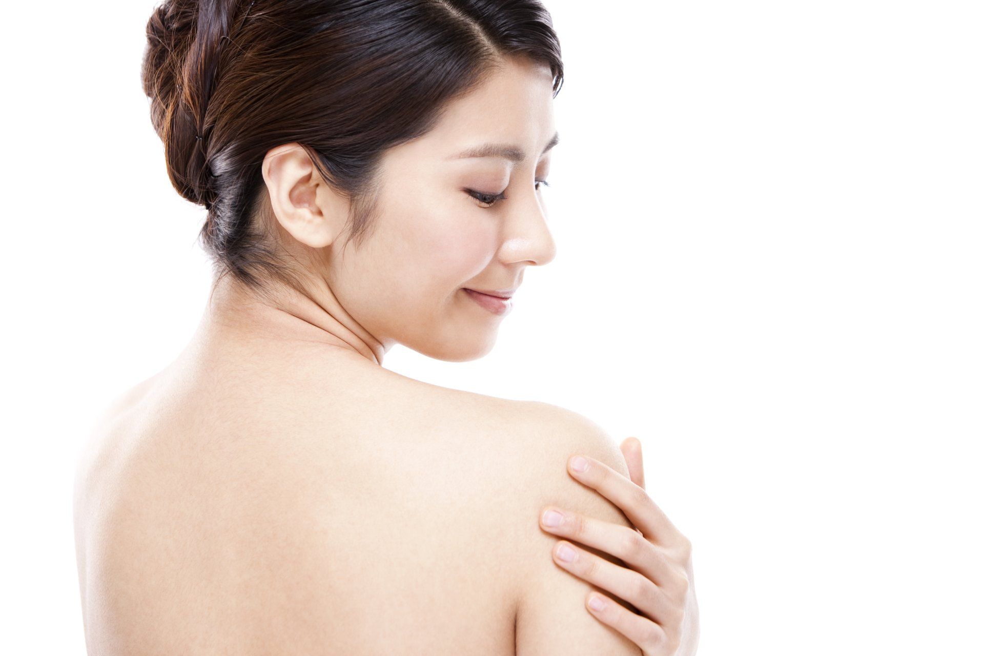A woman is touching her shoulder with her hand.