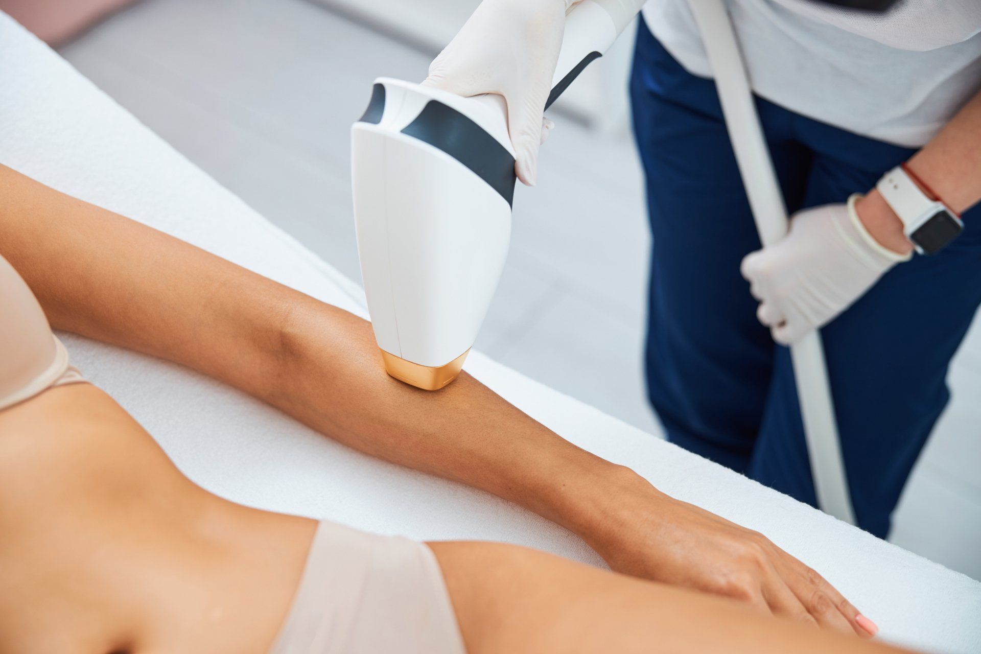 A woman is getting a laser hair removal treatment on her arm.