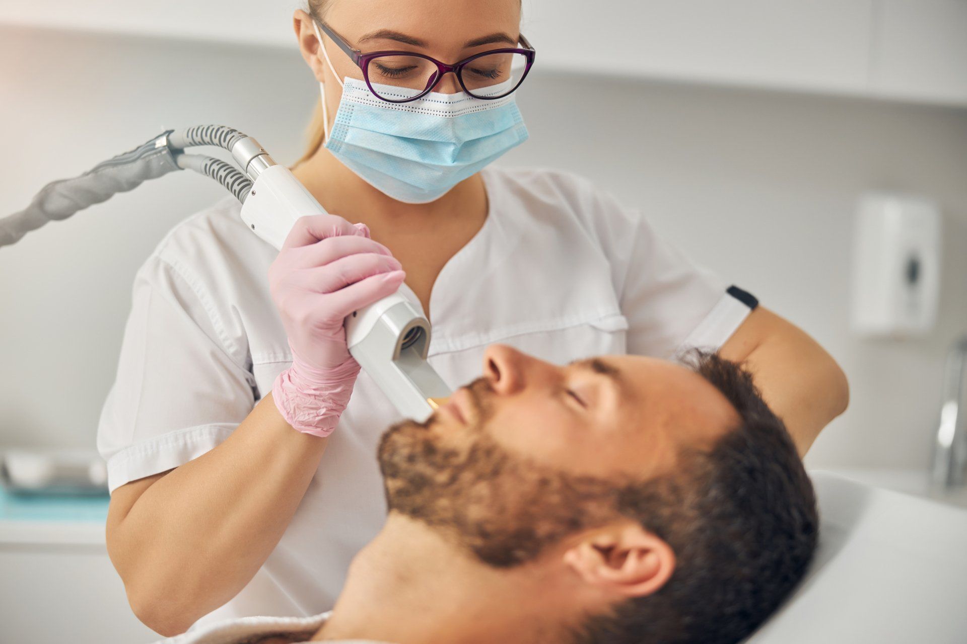 A man is getting a laser treatment on his face.