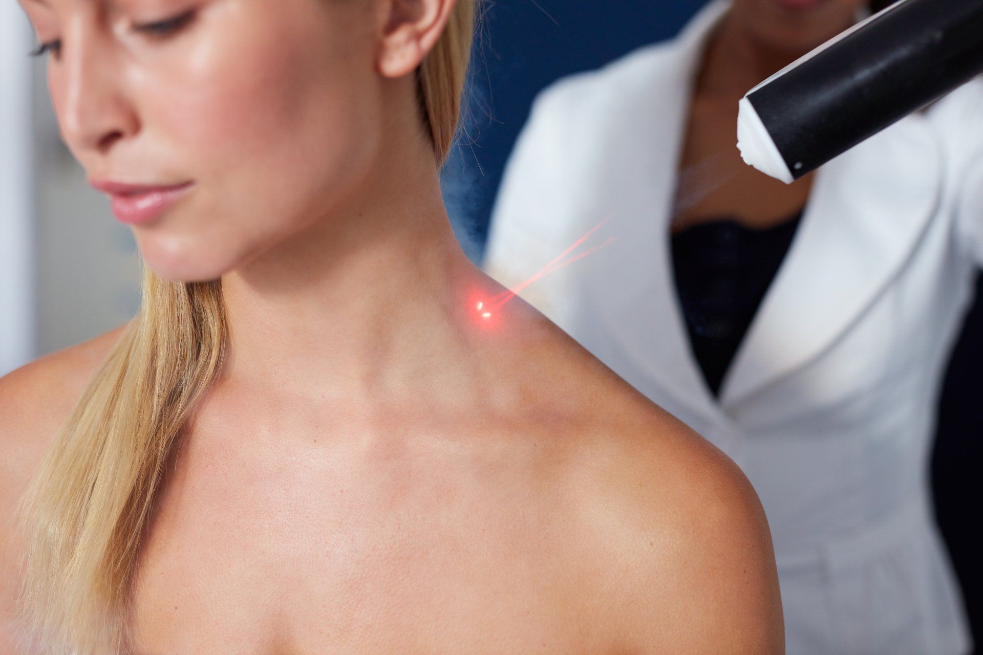 A woman is getting a laser treatment on her shoulder.
