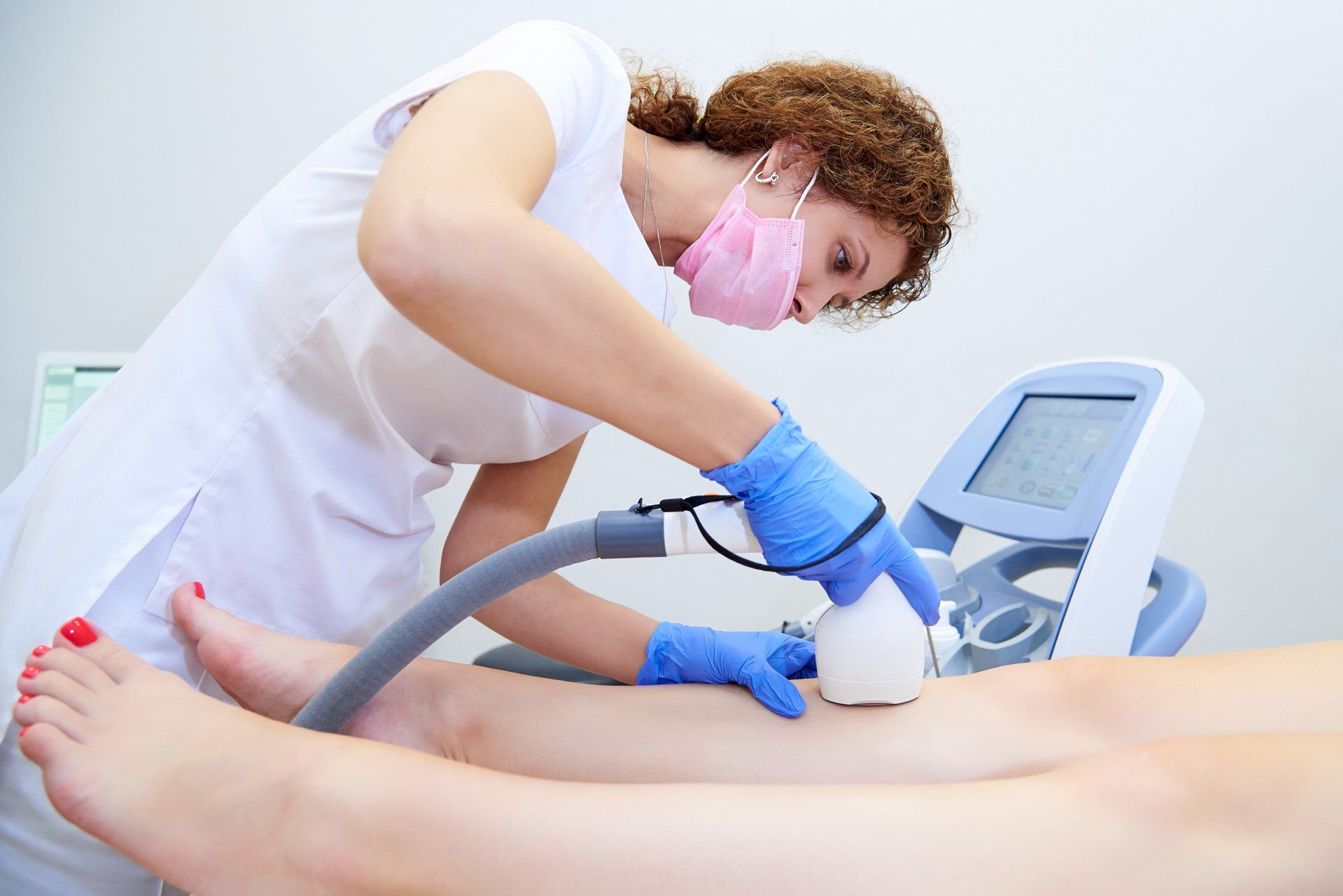 A woman is using a machine to remove hair from a woman 's leg.