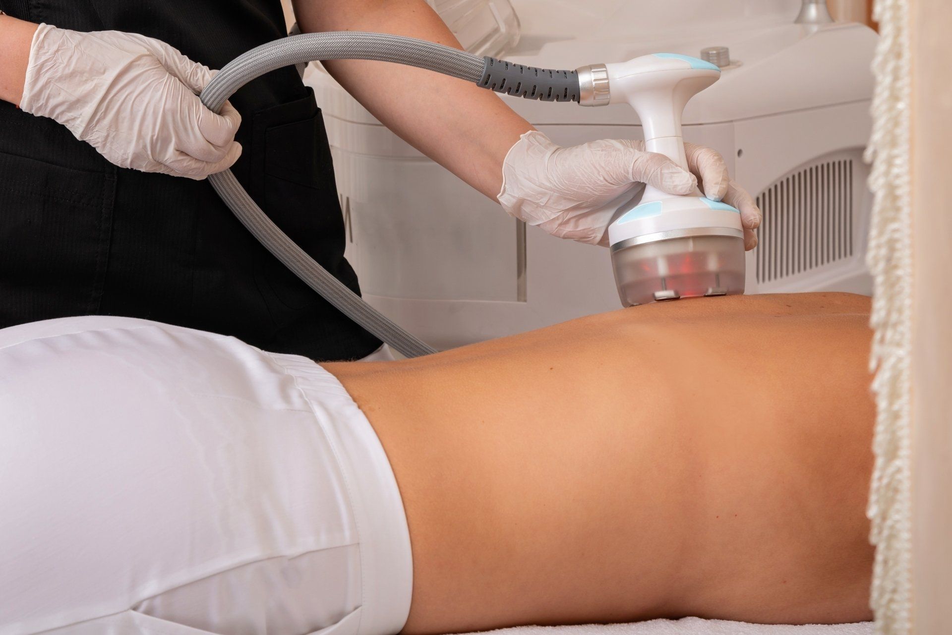 A woman is getting a cavitation treatment on her back.