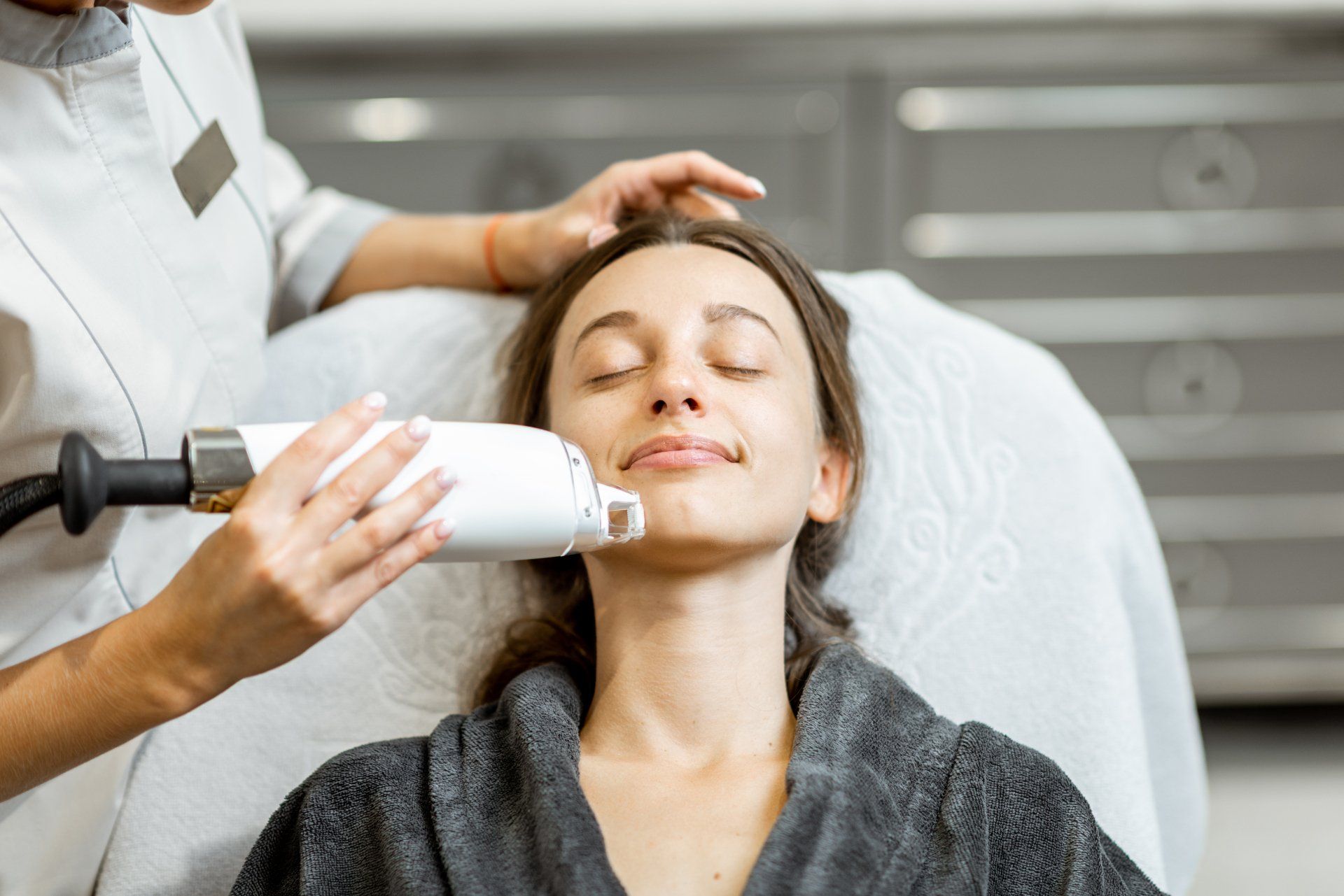 A woman is getting a laser treatment on her face.