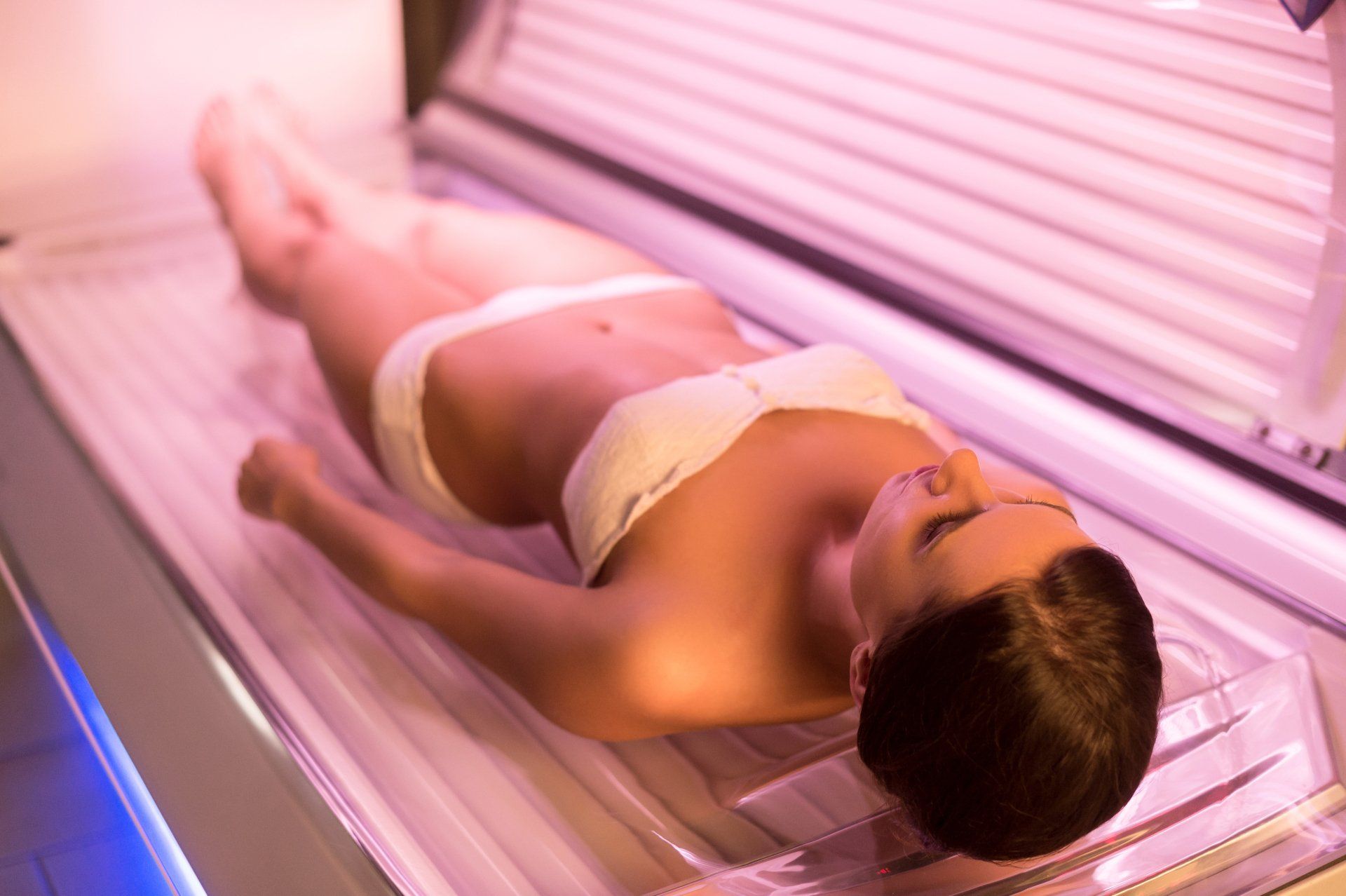 A woman in a bikini is laying in a tanning bed.