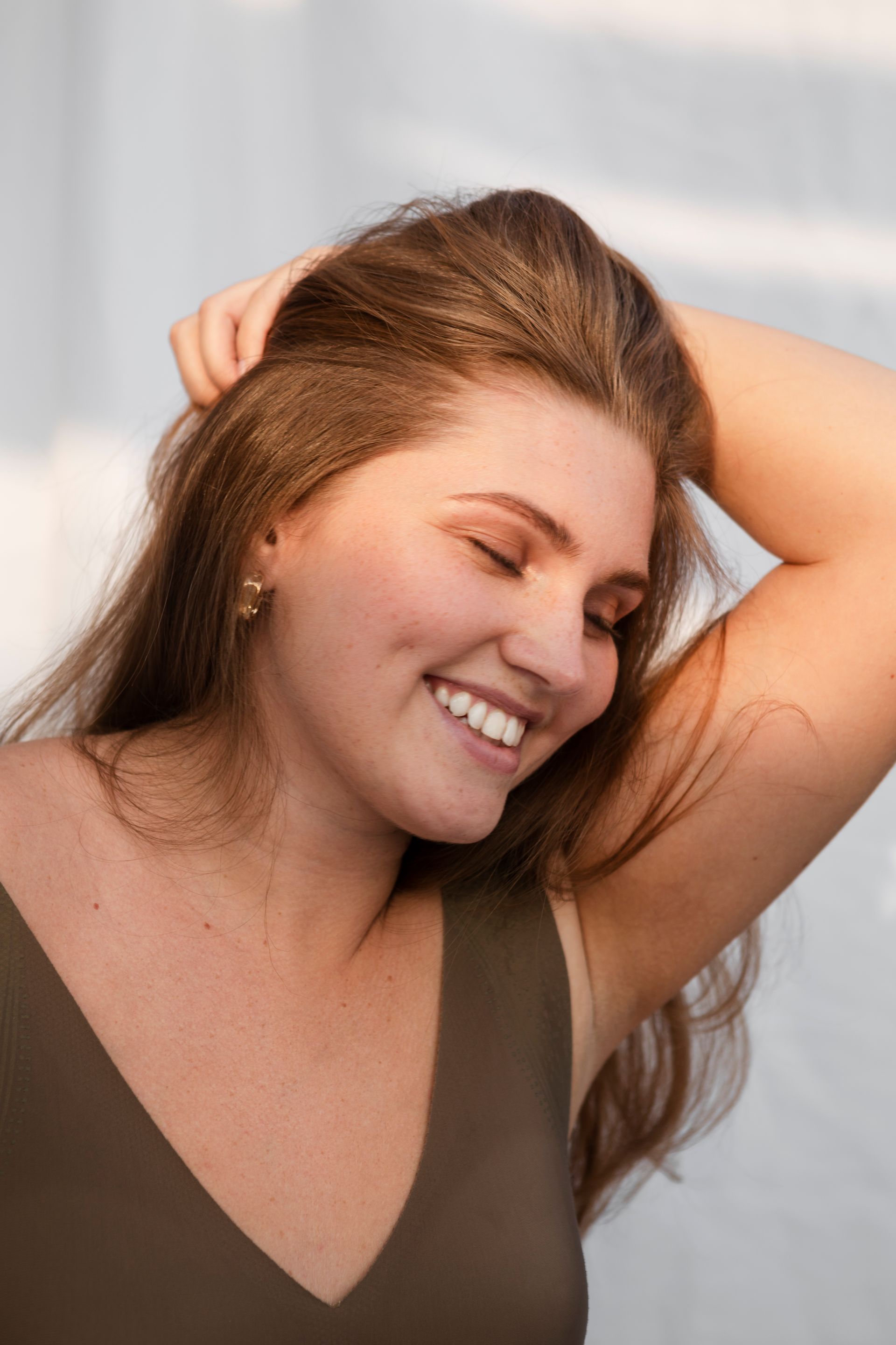 A woman is smiling with her hand in her hair.