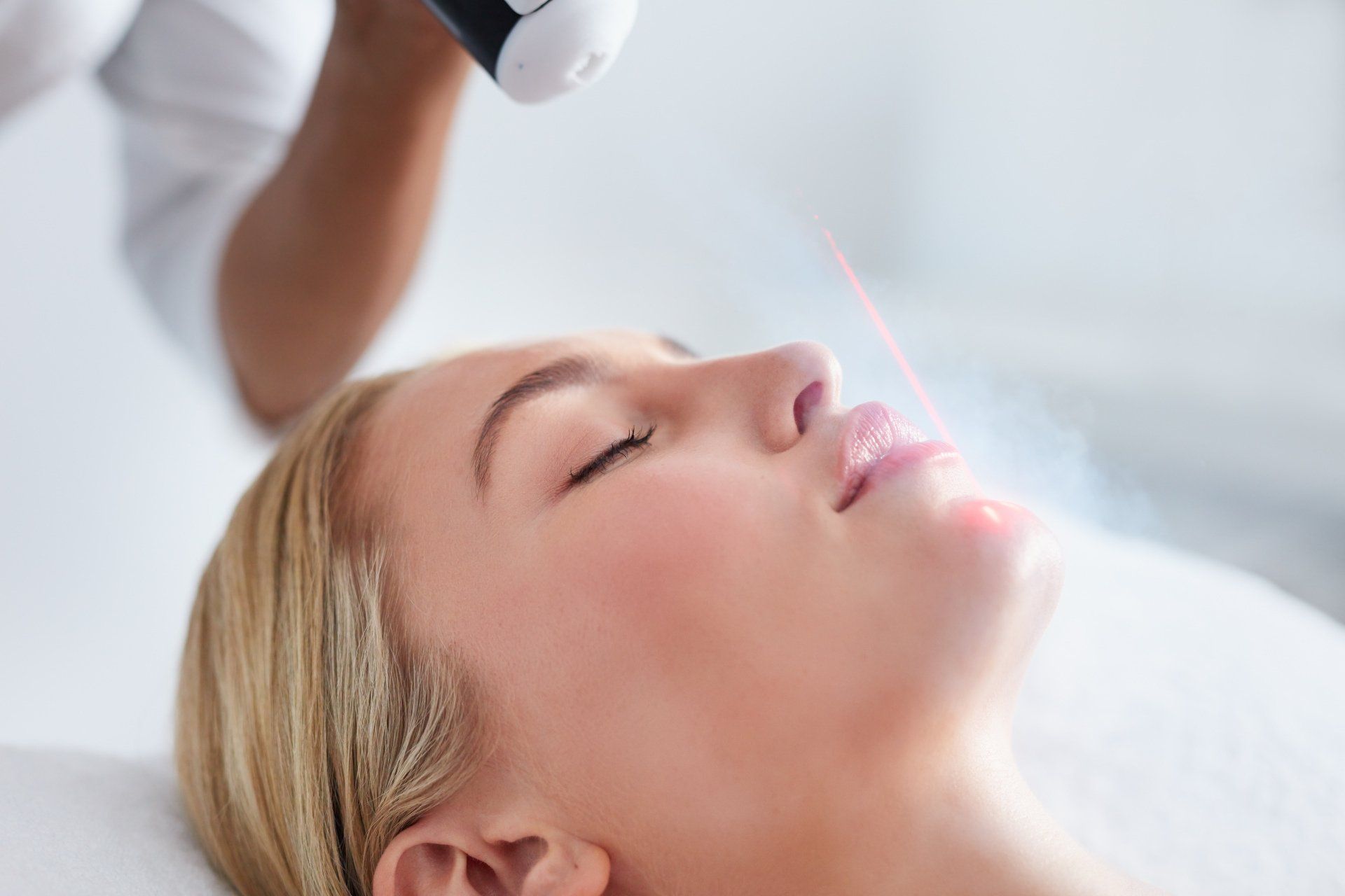 A woman is getting a laser treatment on her face.