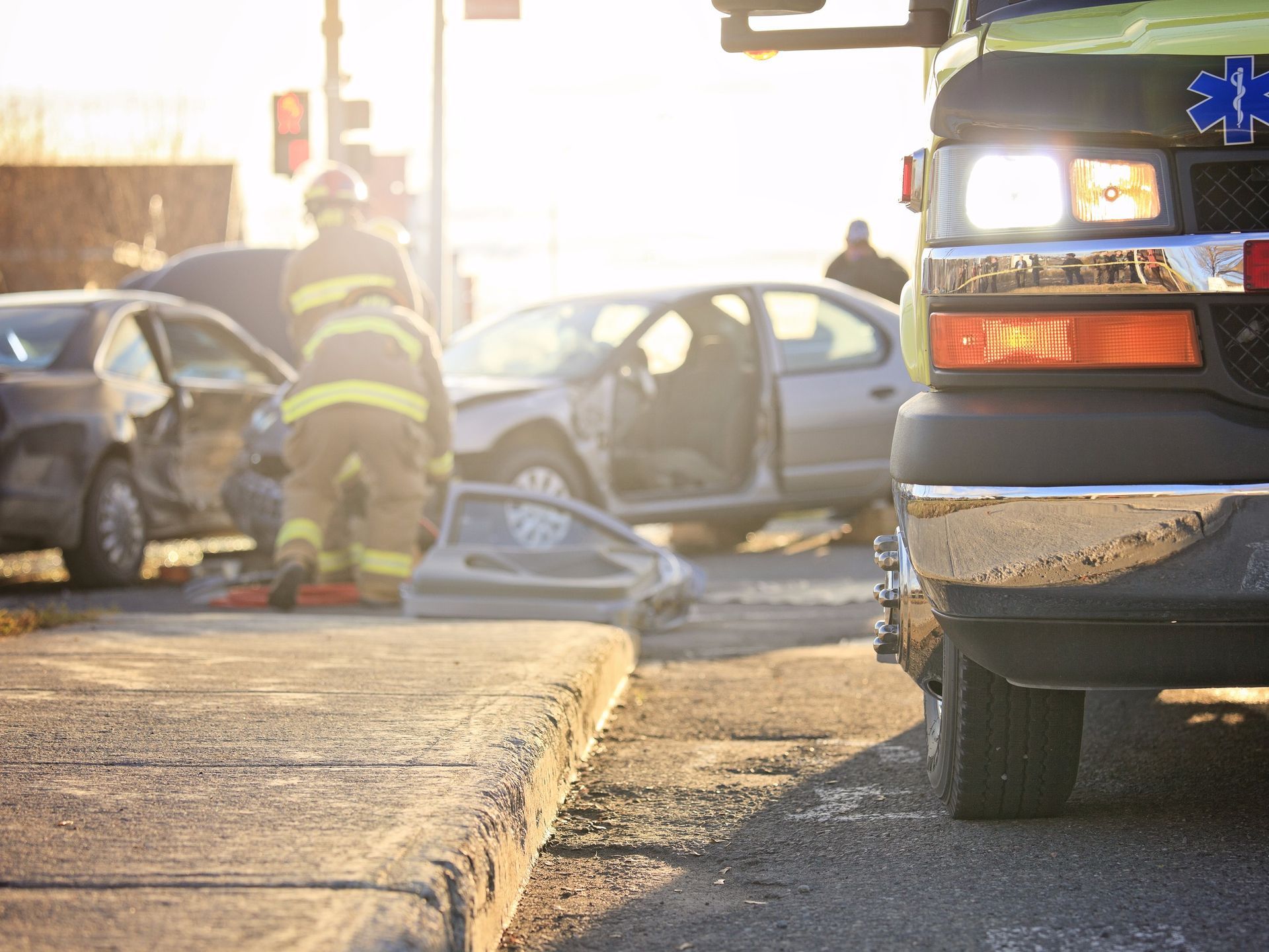A firefighter and an ambulance are at the scene of a car accident.