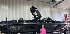 A woman is standing next to a black boat in a garage.