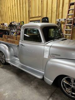 A silver truck is parked in a garage next to a ladder.