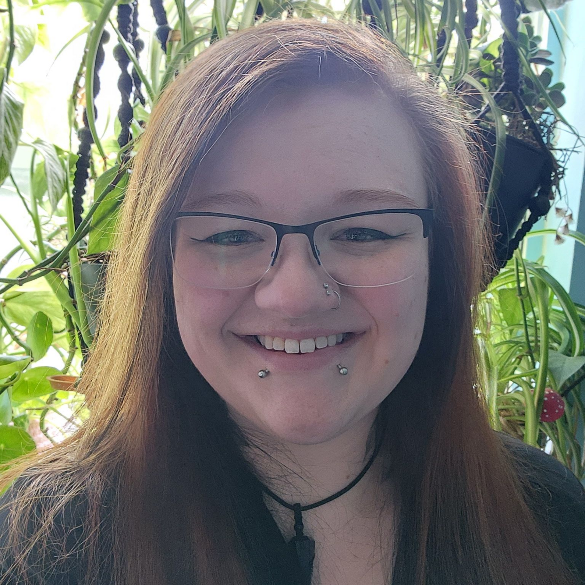 A woman with curly hair is smiling and wearing a green shirt.