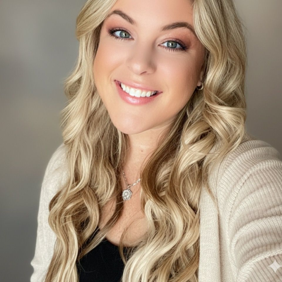A woman with blonde hair is smiling and wearing a black shirt.