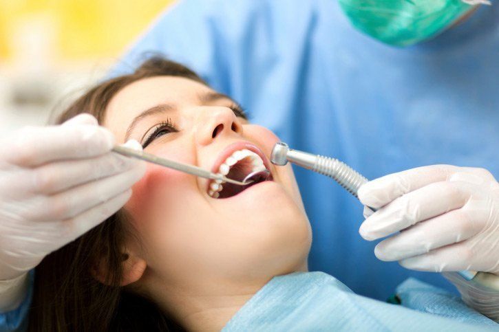 A woman is getting her teeth examined by a dentist.