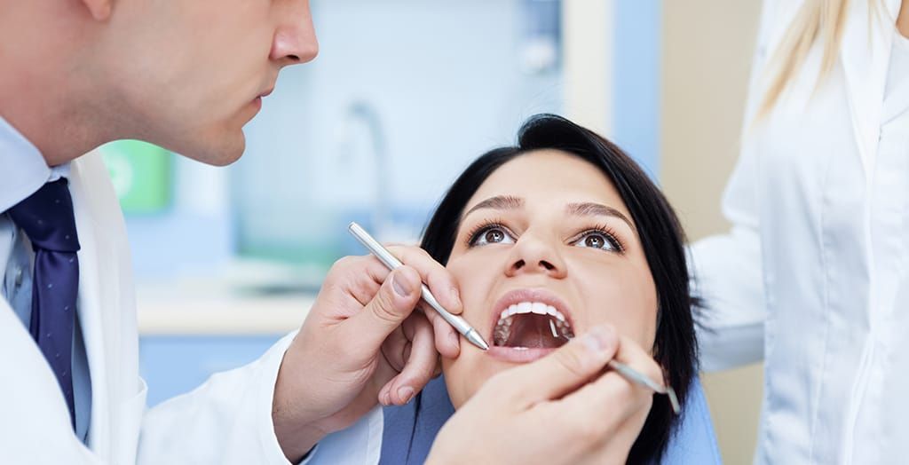 A woman is getting her teeth examined by a dentist.