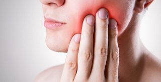 A woman is holding her mouth in pain because of a toothache.