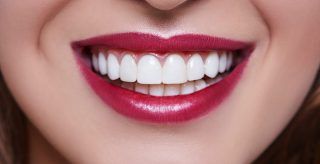 A close up of a woman 's mouth with white teeth and red lipstick.