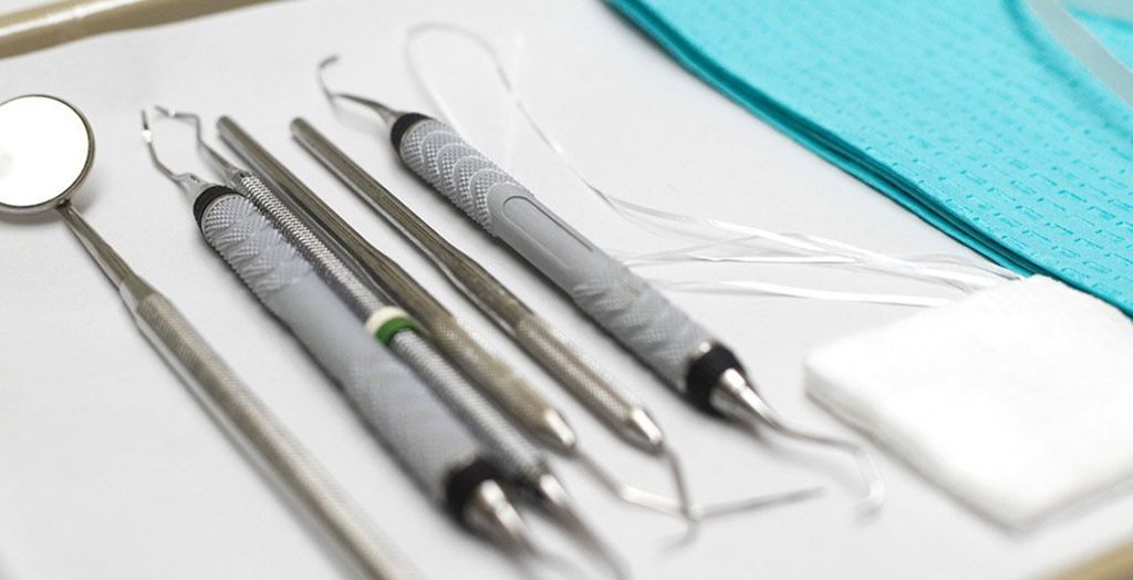 A tray of dental instruments including a mirror and tweezers