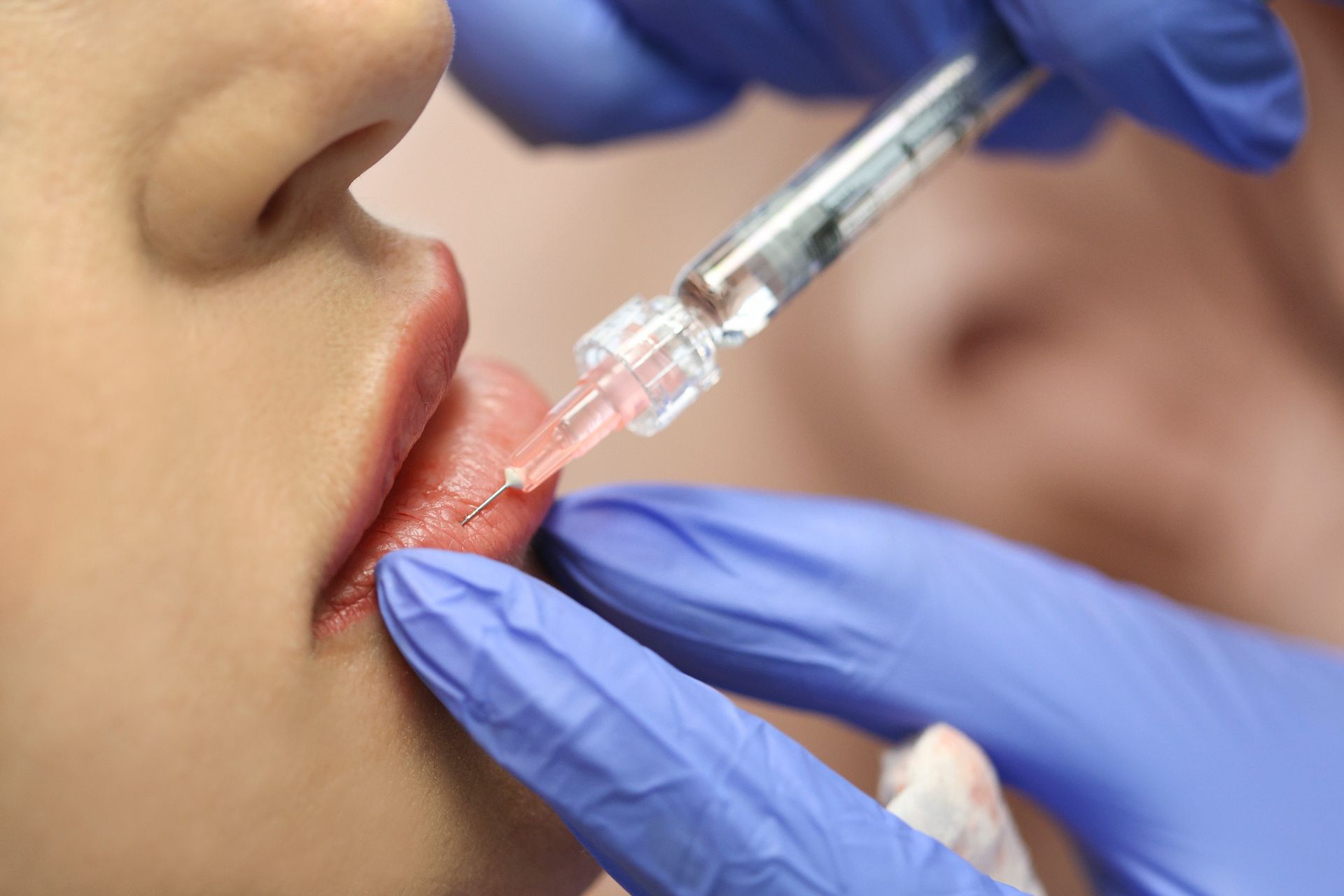 A woman is getting a botox injection in her lips.