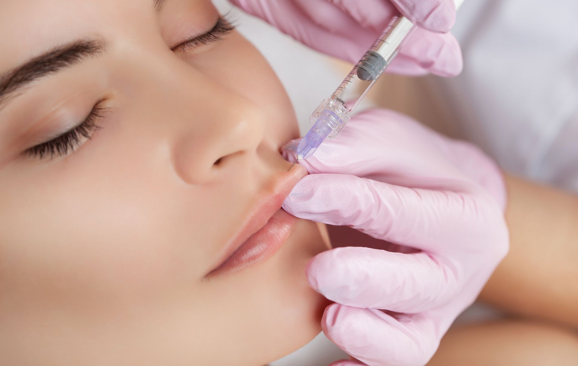 A woman is getting a botox injection in her lips.