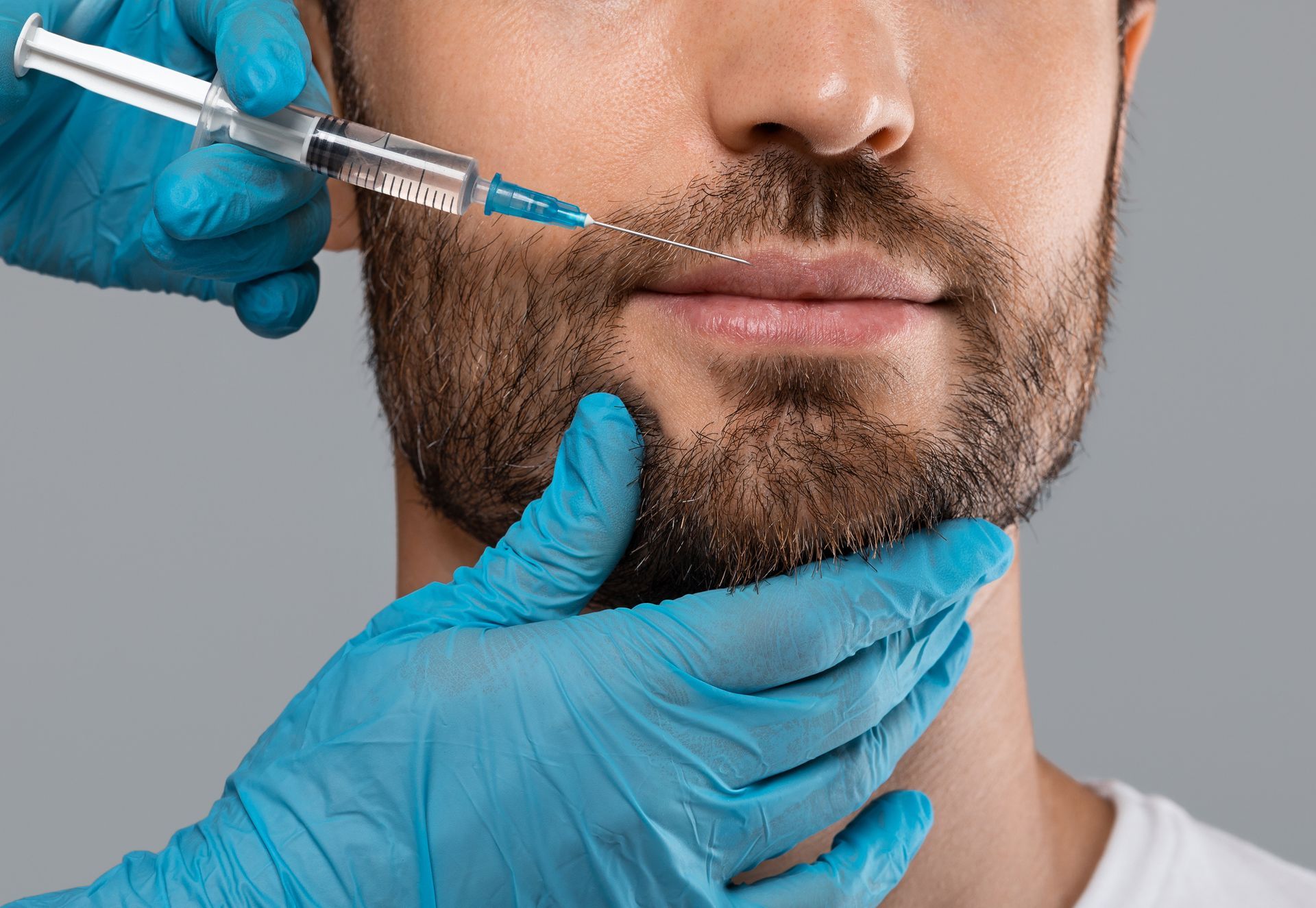 A man with a beard is getting a botox injection in his lips.