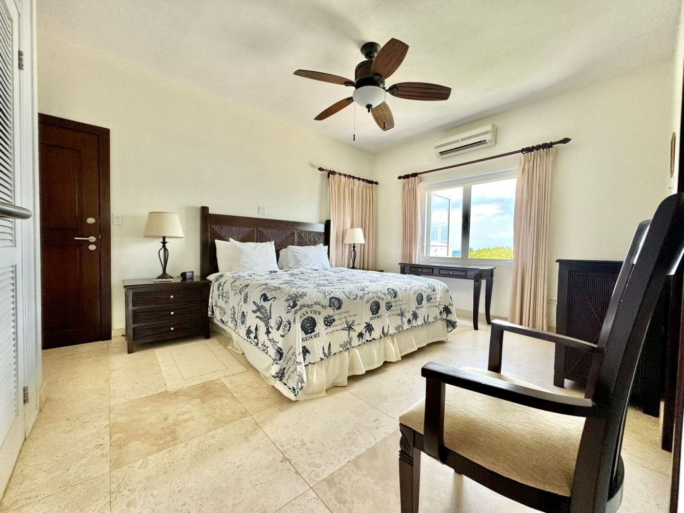 Bedroom with bed, nightstands, desk, chair, window with curtains, and a ceiling fan.