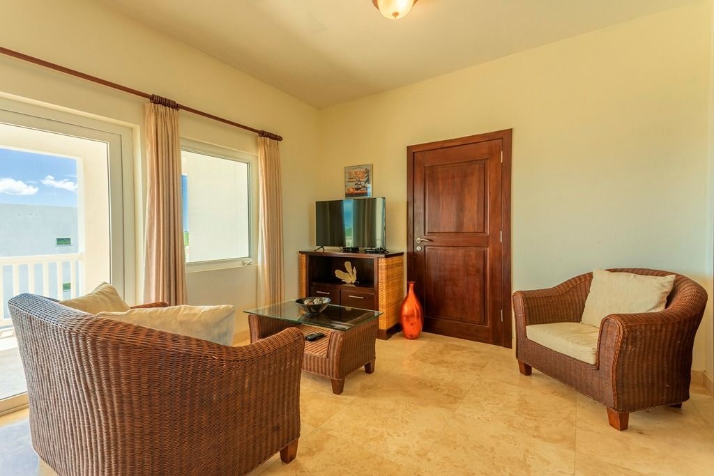 Living room with wicker furniture, TV, and balcony access.
