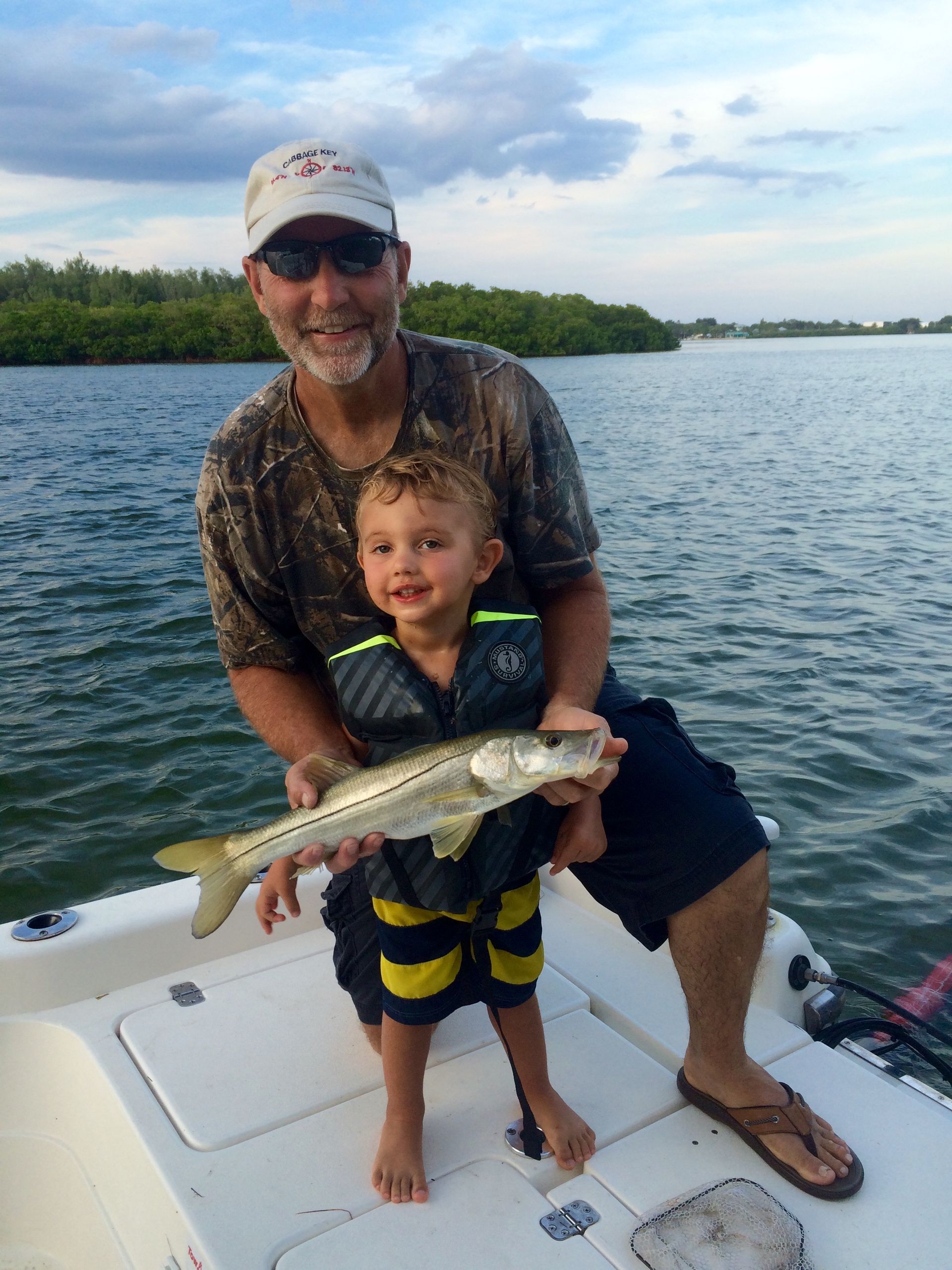 A man and a boy are sitting on a boat holding a fish.