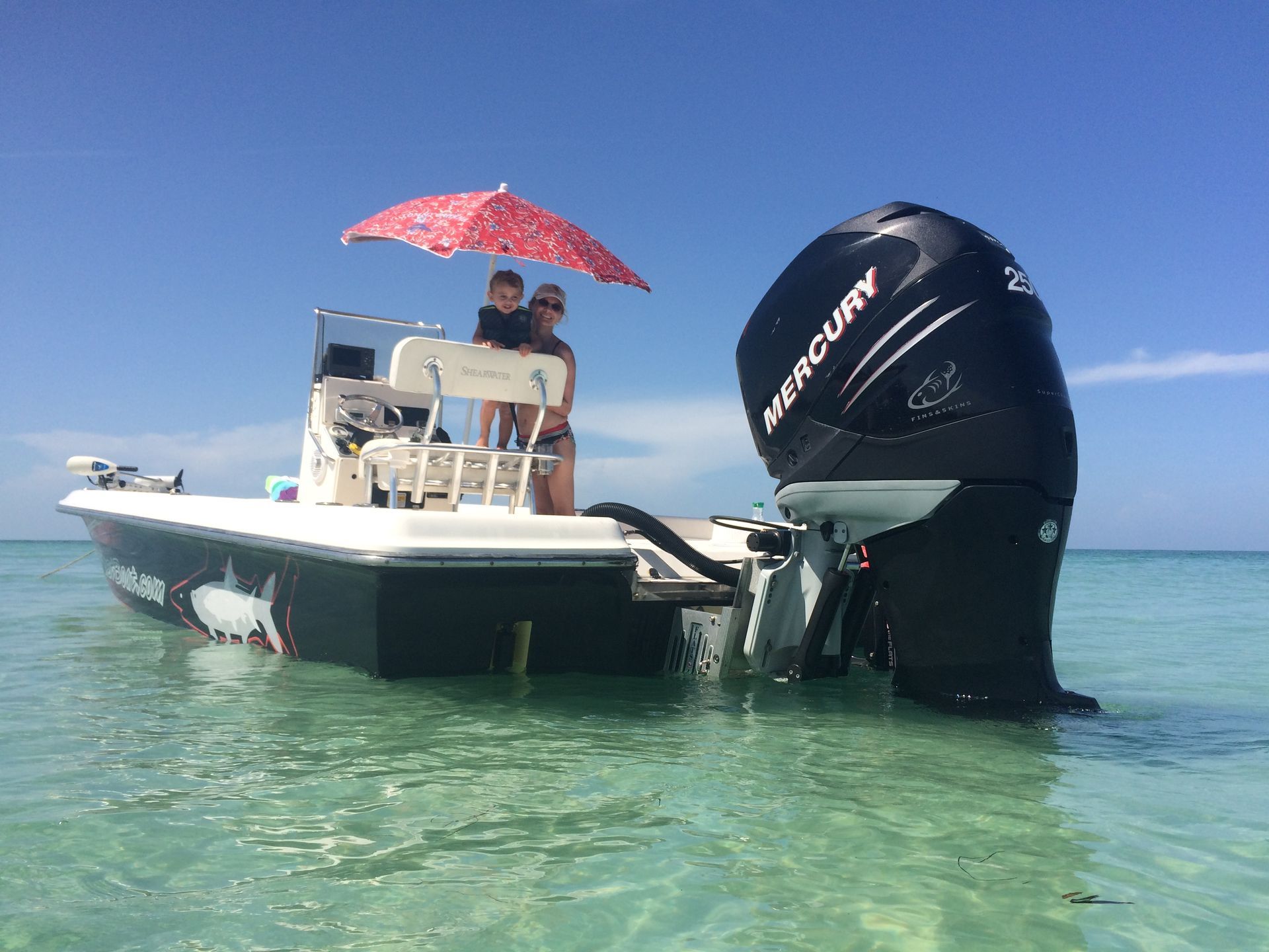 A couple is sitting on a boat in the ocean under an umbrella.