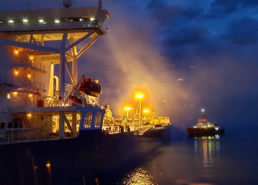 A large ship is docked in the water at night.