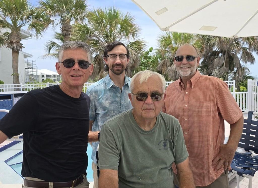 A group of men are posing for a picture in front of a pool.