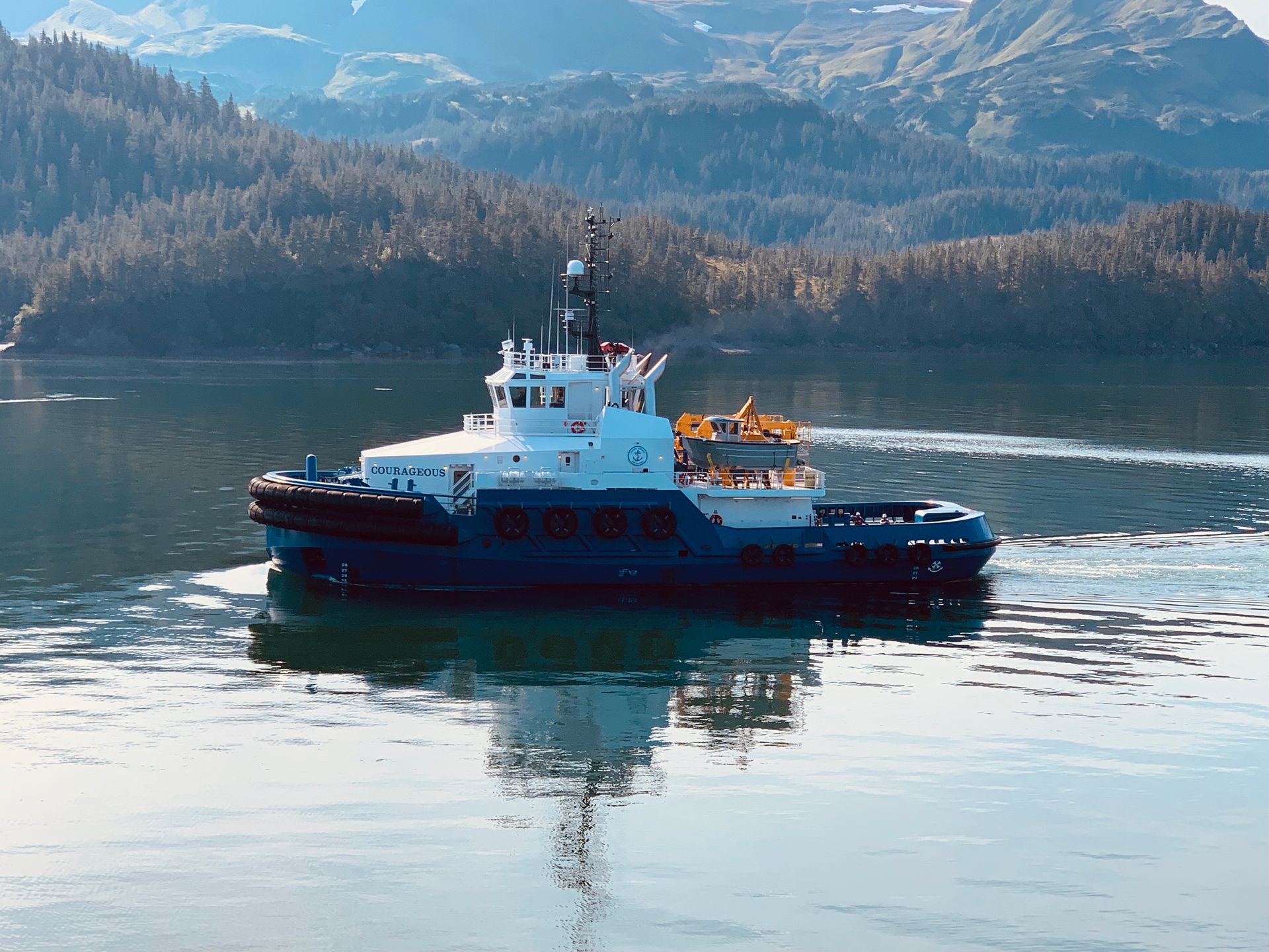 A boat is floating in the water with mountains in the background