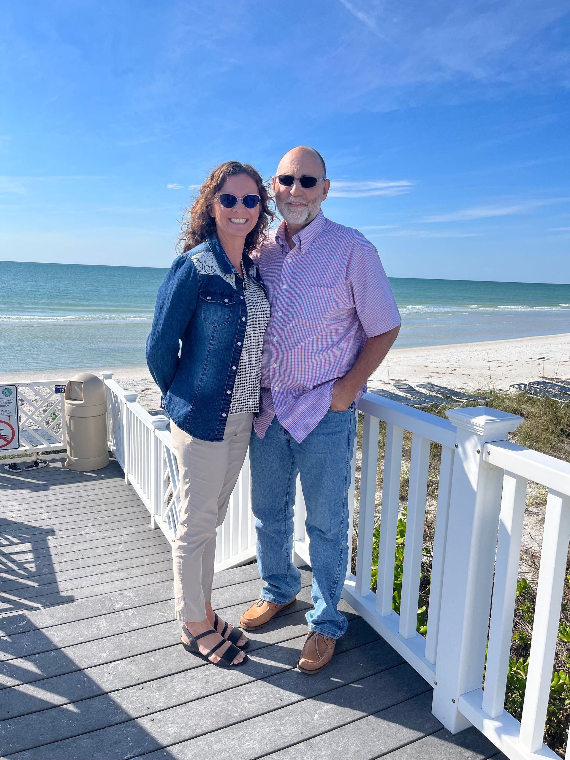 A man and a woman are standing next to each other on a deck overlooking the ocean.