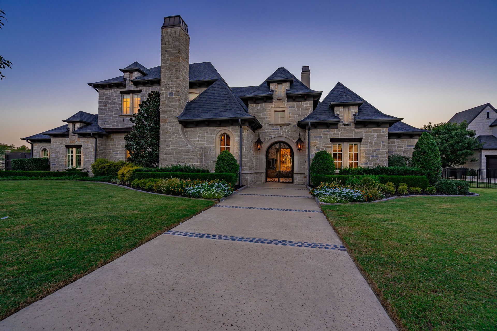 A large stone house with a concrete driveway leading to it.