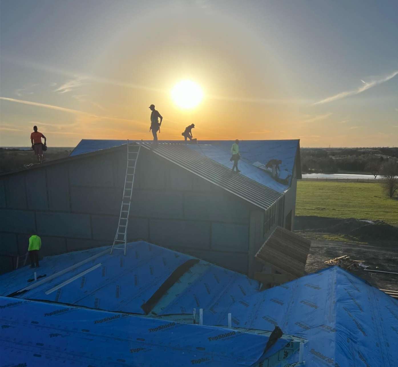 A group of people are working on the roof of a house.